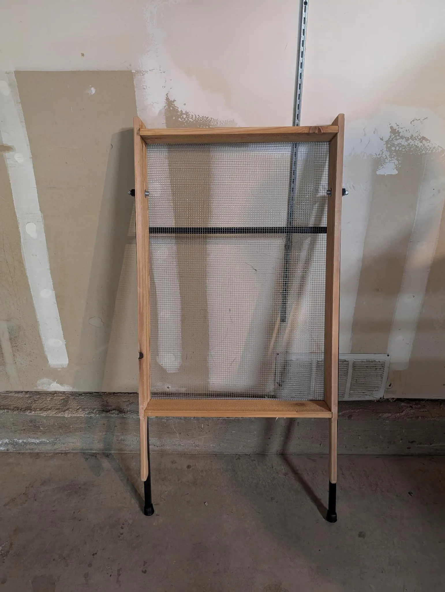 Cedar-framed sifting screen standing on its folding steel legs